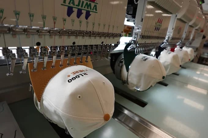 Embroidery machines creating San Marcos custom hats in a production facility.